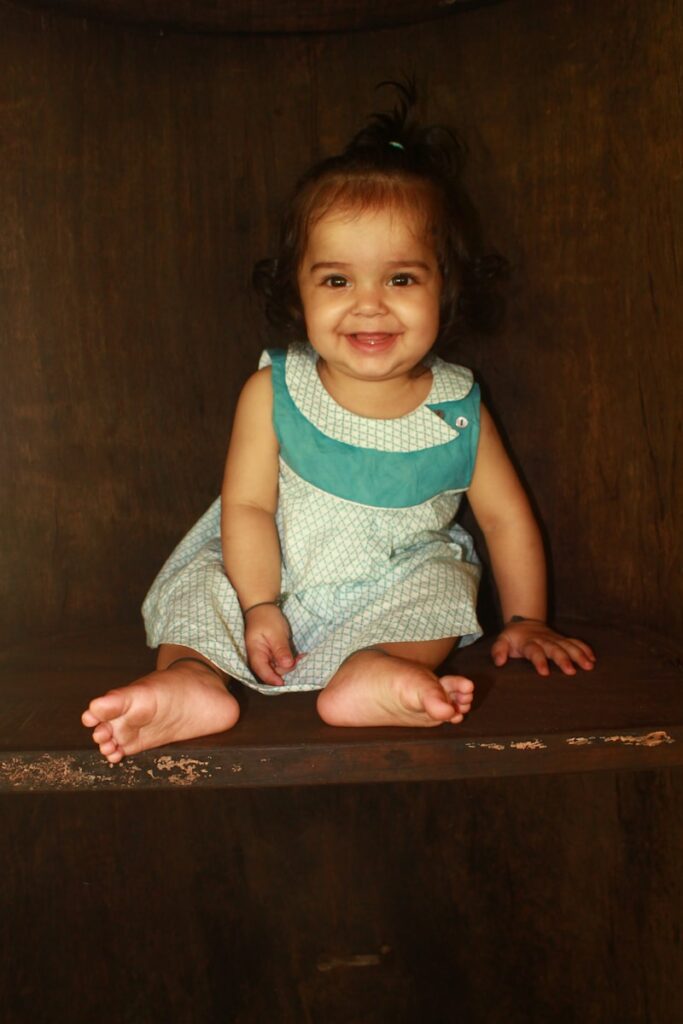 A little girl sitting on top of a wooden shelf