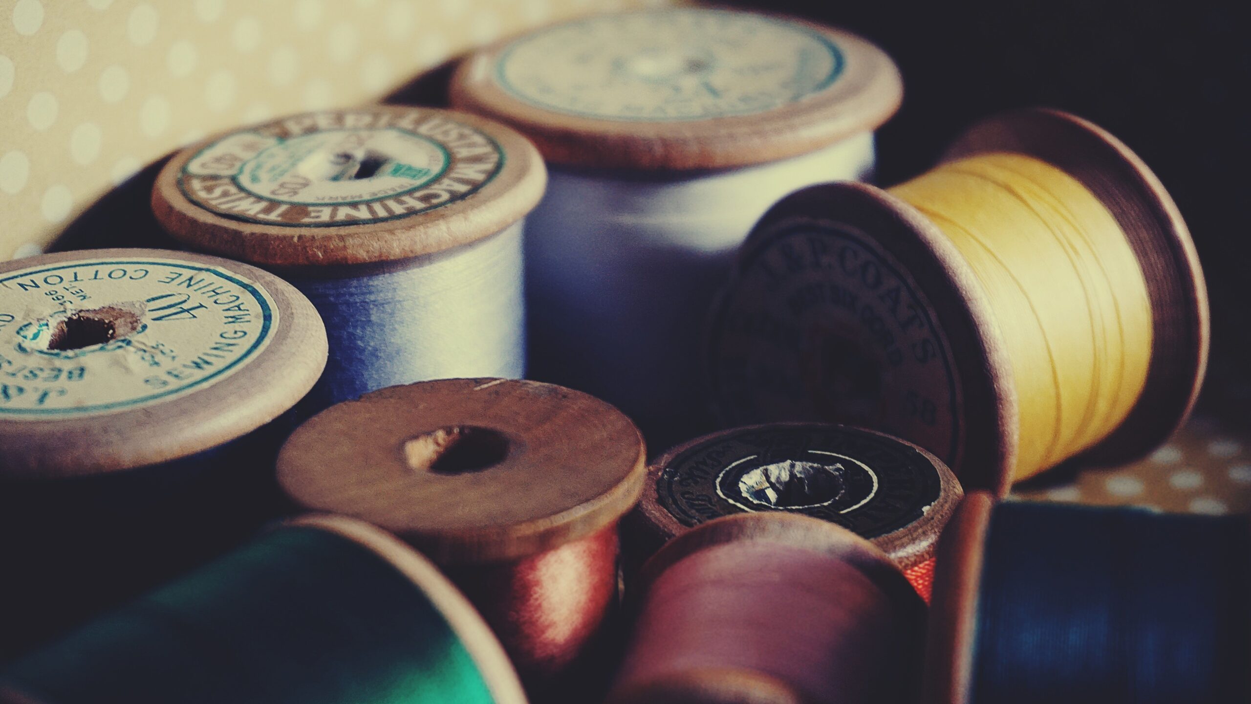 Qu'est ce qu'une fibre synthétique ? Peppita A close-up of vintage wooden spools displaying colorful sewing threads for crafting and tailoring.